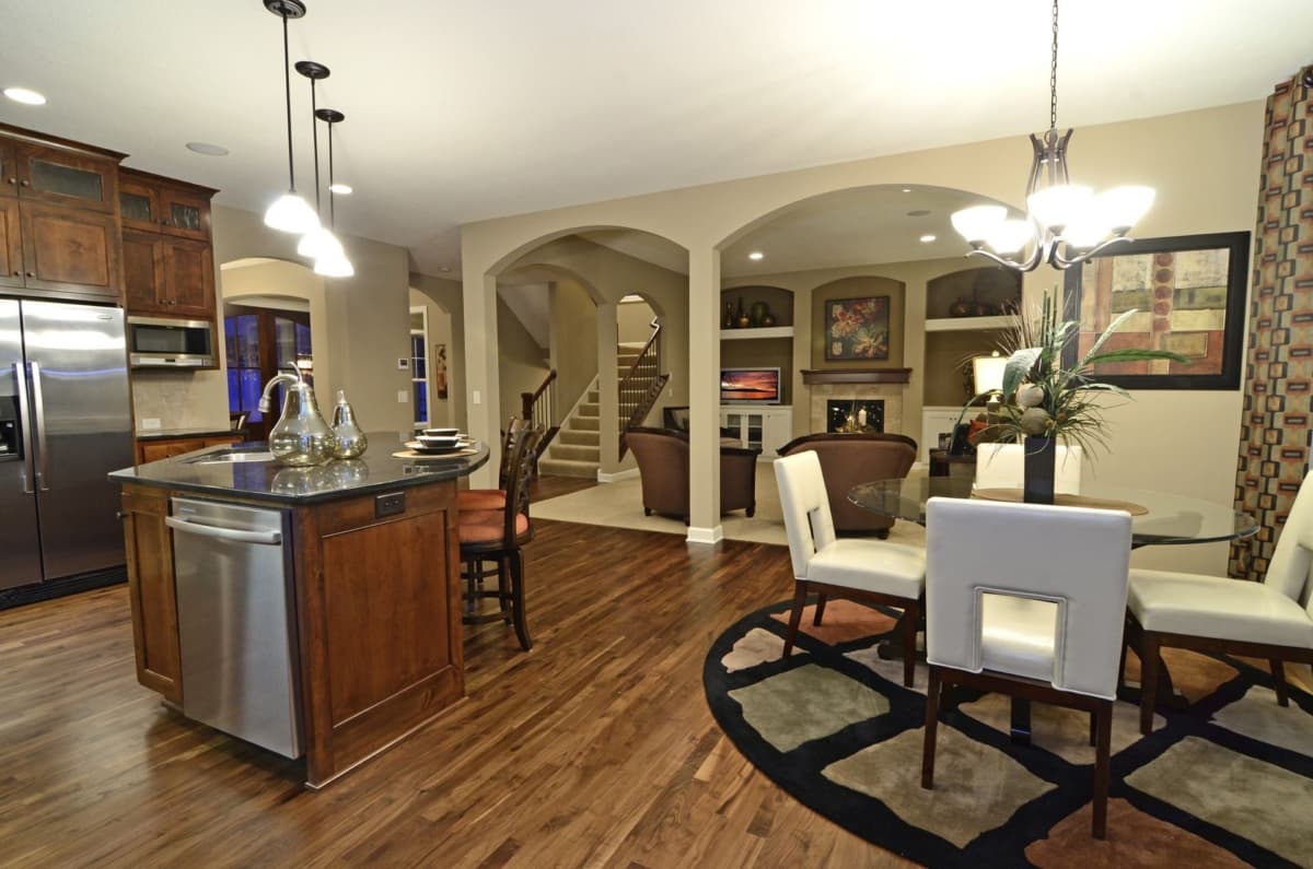 Open concept living area with kitchen island, dining area, and living room featuring fireplace and built-in shelves.
