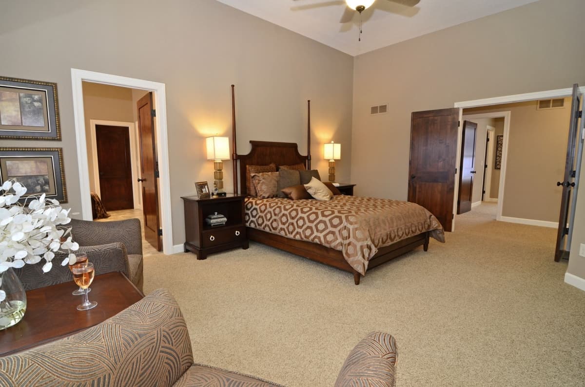 Primary bedroom with vaulted ceiling, wooden four-poster bed, and two doorways opening to hallway.