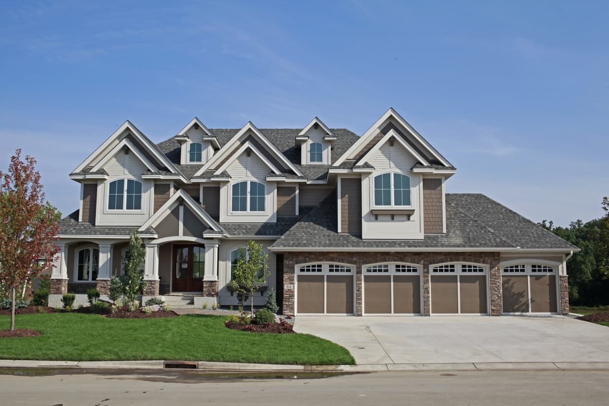 House plan exterior. Two-story home with a gabled roof, multiple dormers, and a three-car garage. Features a covered entry porch.