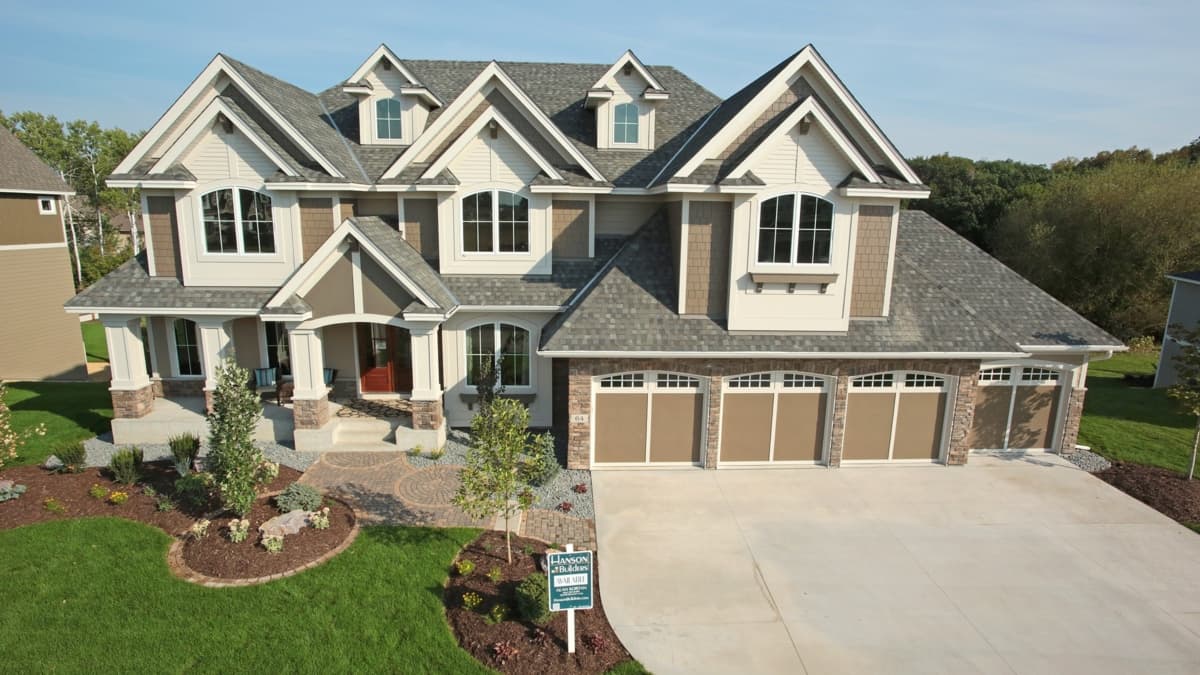 House plan exterior: two-story, Multiple gables, dormers, covered porch with stone pillars, and a three-car garage.