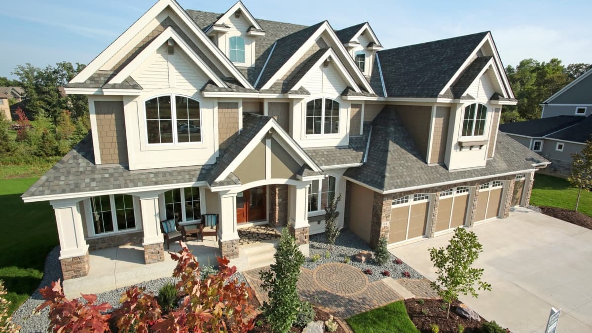 Two-story house plan exterior with arched windows, dormers, a covered porch, and a three-car garage.