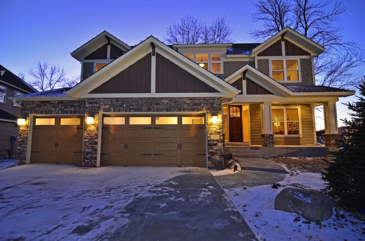 Craftsman style house plan exterior with three-car garage, stone accents, gables, and covered front porch.