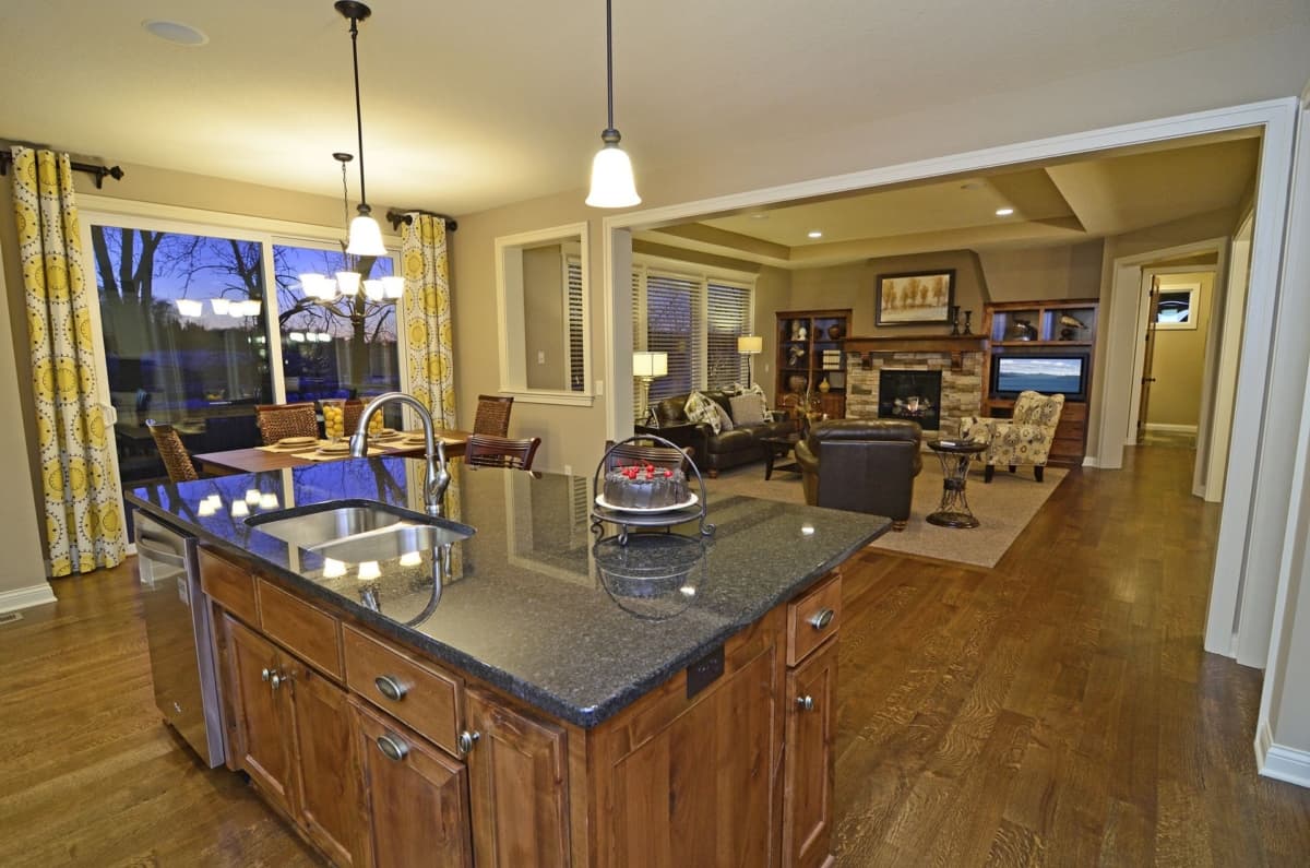 Interior view of a home with a kitchen island, dining area, and living room featuring a fireplace and built-in shelving.