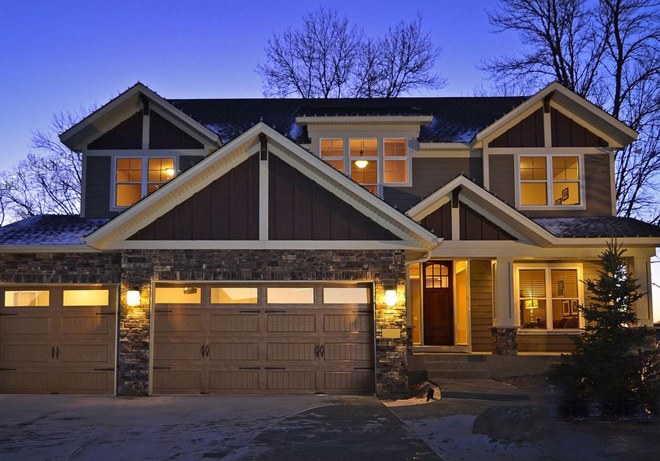 Modern farmhouse house plan exterior with three garage bays, stone accents, gables, and a covered entry.