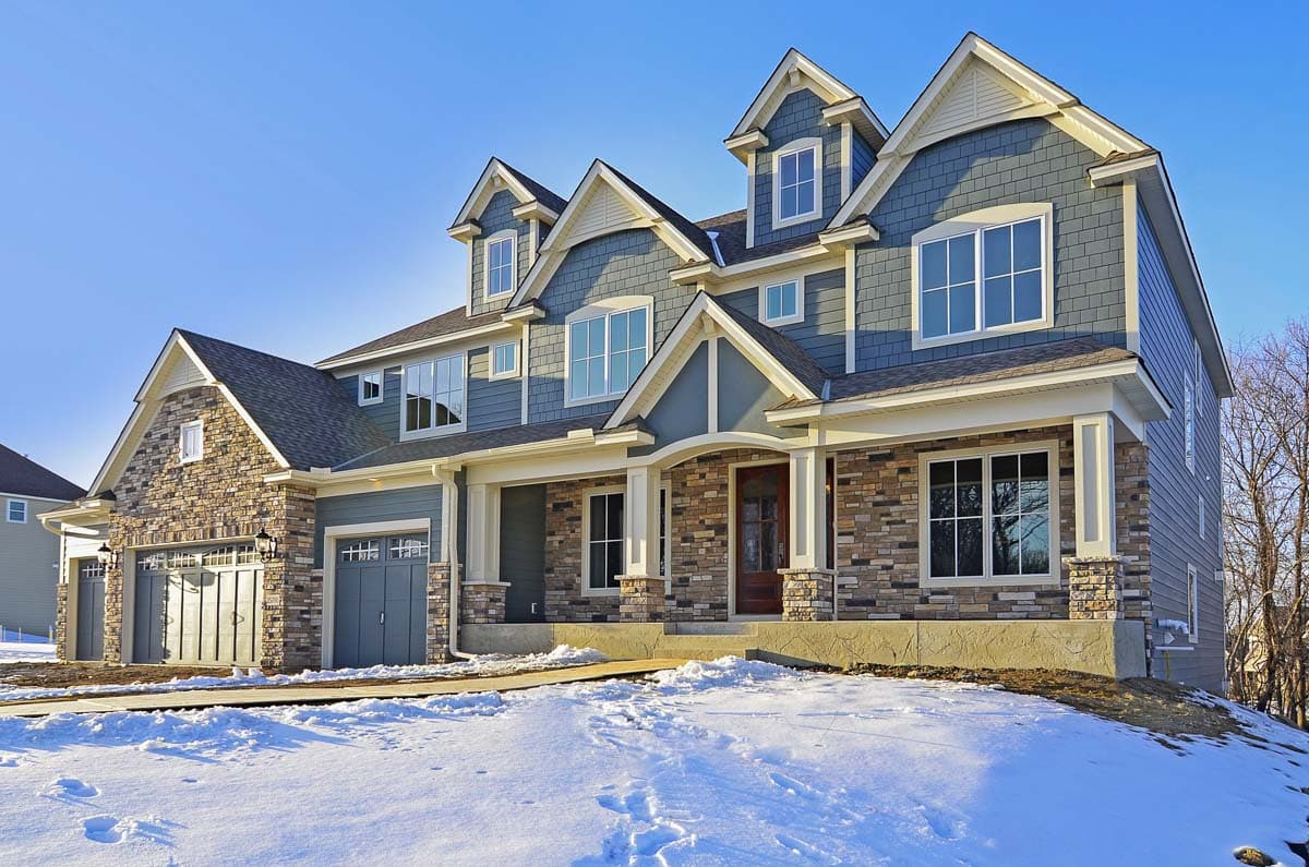 House plan exterior: Two-story dwelling with stone accents, multiple gables, dormers, and a three-car garage.