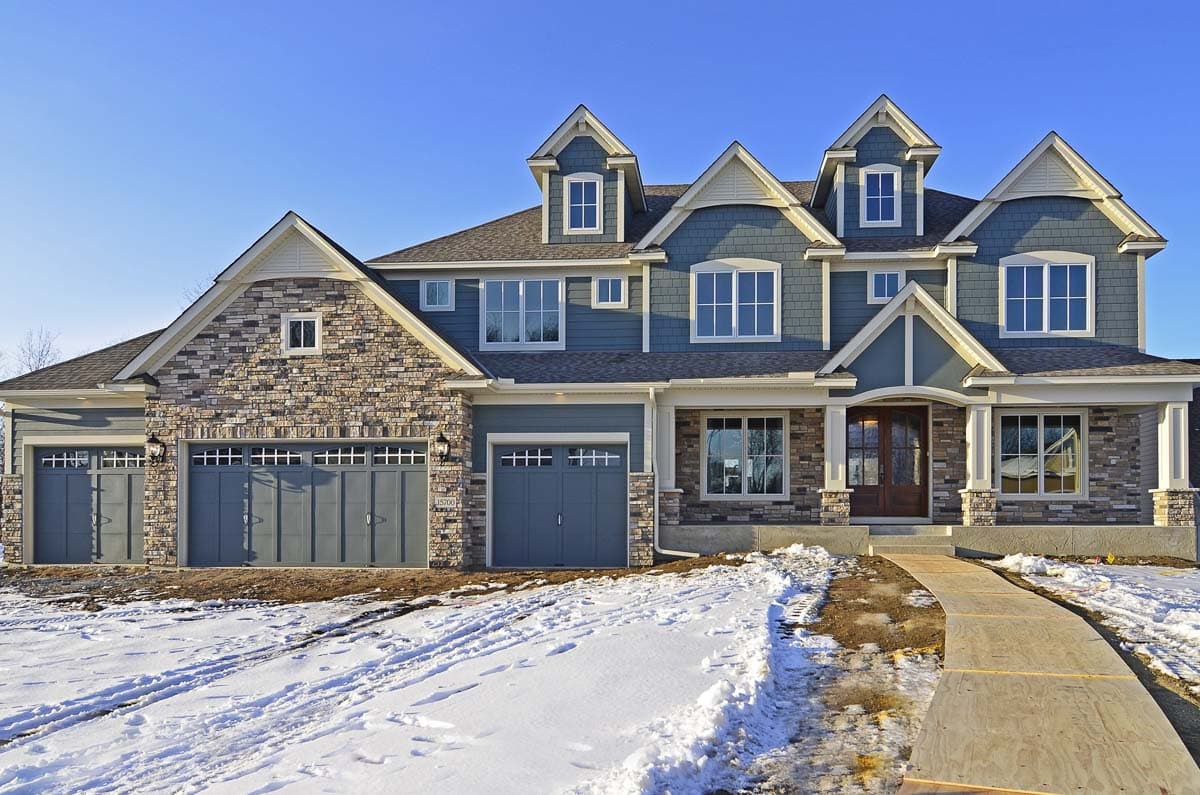 Two-story house plan exterior with multi-gabled roof, stone accents, dormers, and a four-car garage.