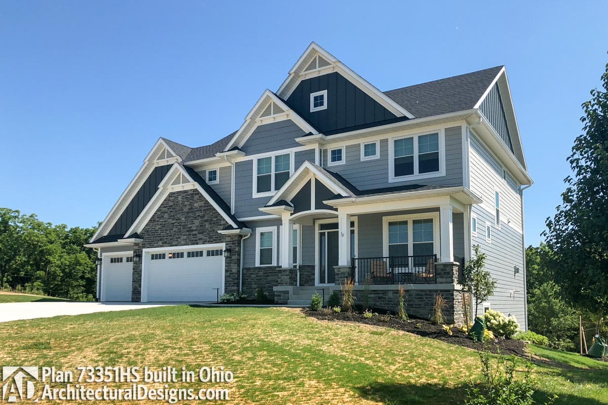 House plan exterior: Two-story Modern Farmhouse with a three-car garage, stone accents, prominent gables, and a covered front porch.