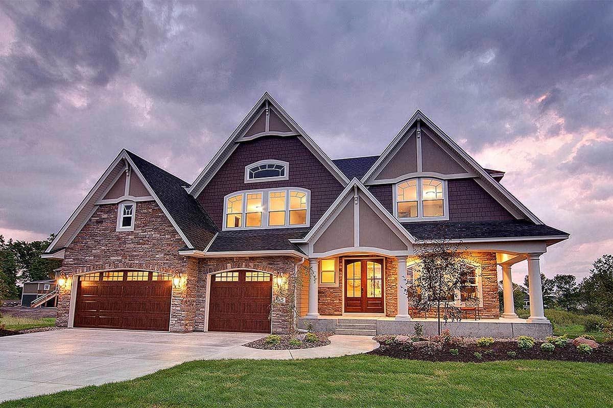 House plan exterior: multi-story home with stone accents, prominent gables, arched windows, and a three-car garage.