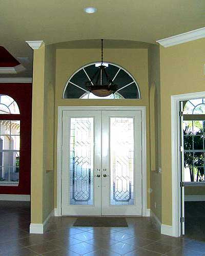 Double entry doors with decorative glass panels topped by a fanlight window. Arched entryway with chandelier.