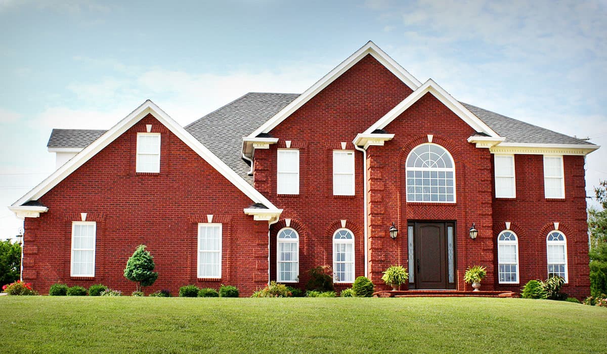 House plan exterior. Two-story brick home with gabled roofline, multiple dormers, and arched window design. Features include a centered front door.
