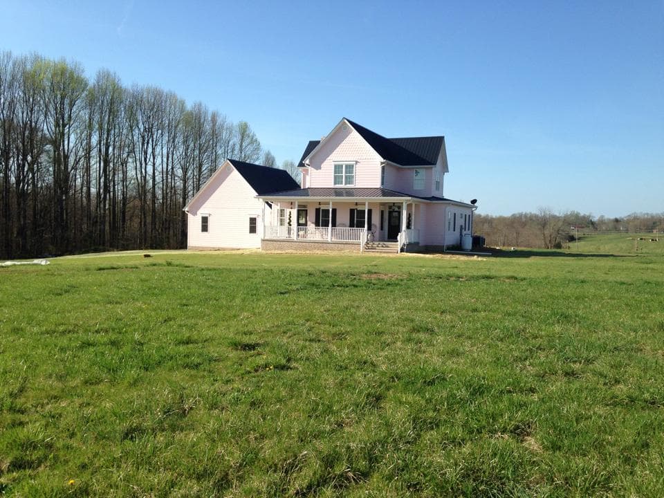 Two-story Modern Farmhouse with wraparound porch, dark metal roof, and gable dormers.