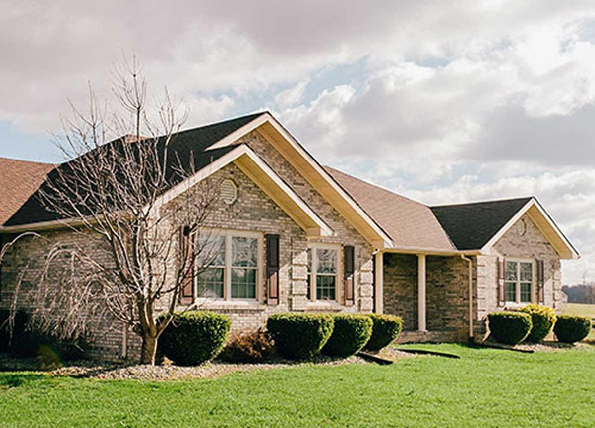 Ranch-style house plan exterior with brick facade, gable rooflines, and covered entryway.