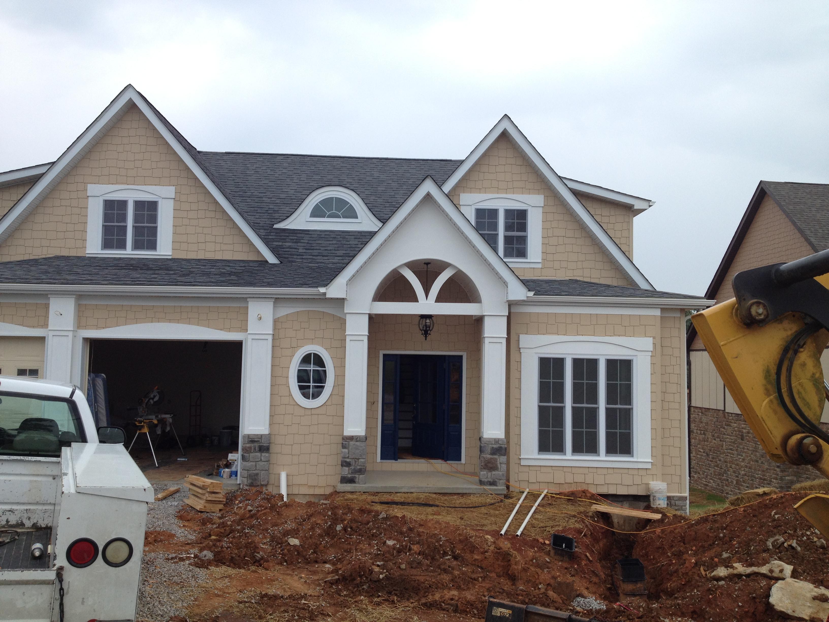 House plan exterior: Two-story home with multiple gables, arched entry, oval window, and attached garage.