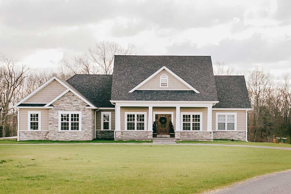 House plan exterior: Ranch-style, single-story home with a covered front porch, stone and siding accents, and multiple gables.