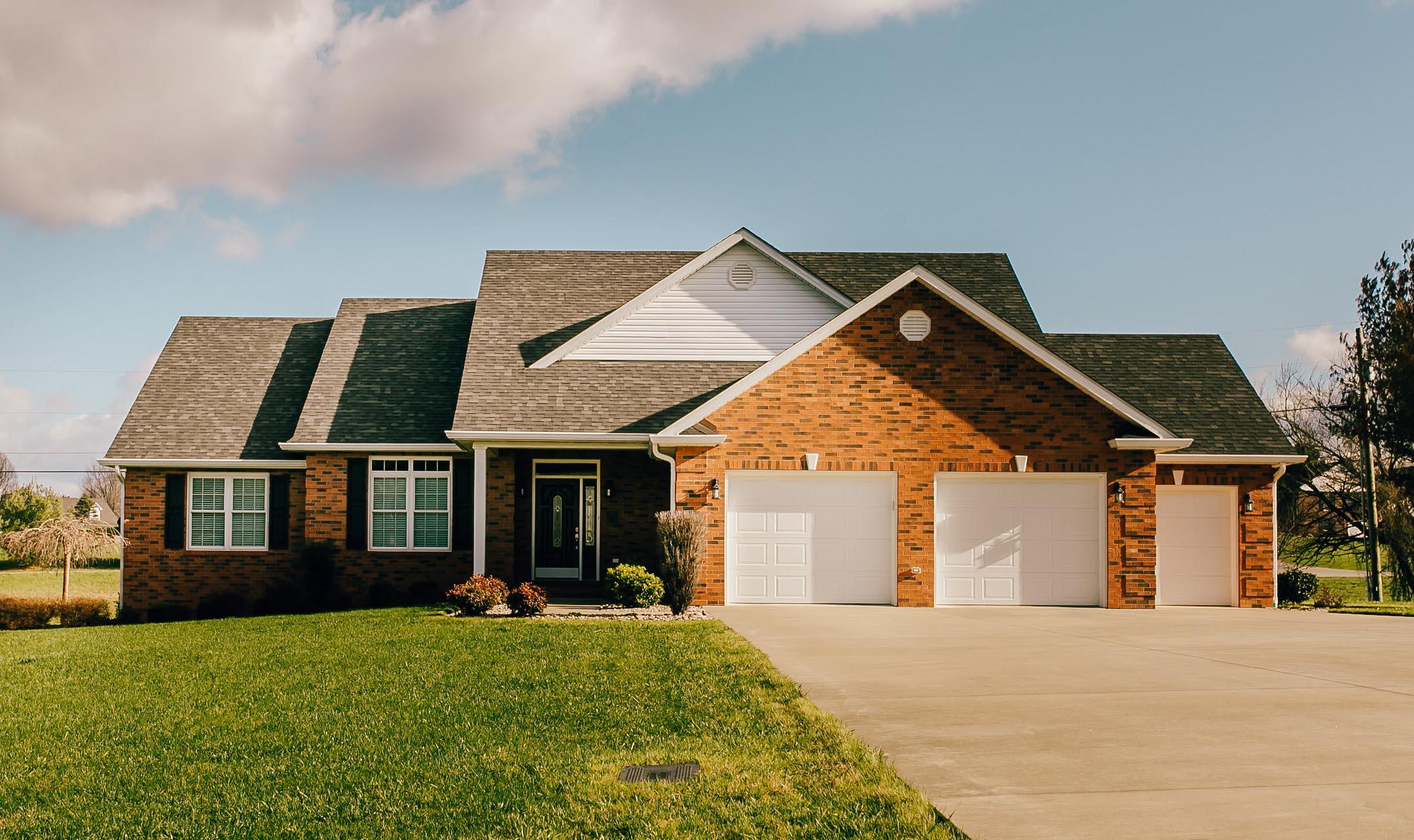 House plan exterior: Brick ranch with a covered entry, three-car garage, and varied rooflines.