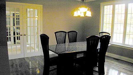 Dining room with glass-paned double doors, dark wood chairs around a granite-top table, and a multi-light chandelier.