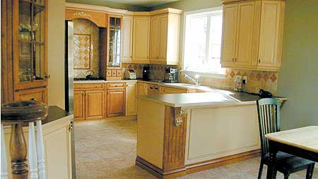 Kitchen interior with a central island, light wood cabinets, granite countertops, tiled backsplash, and a window.