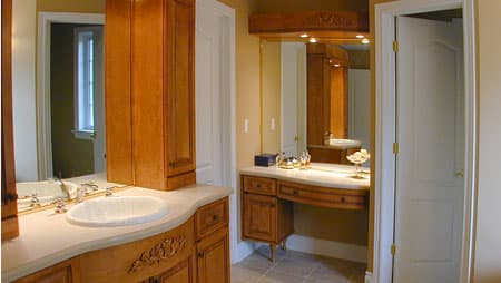 Bathroom vanity with double sinks, wooden cabinetry, and a separate dressing table with mirror and lighting.