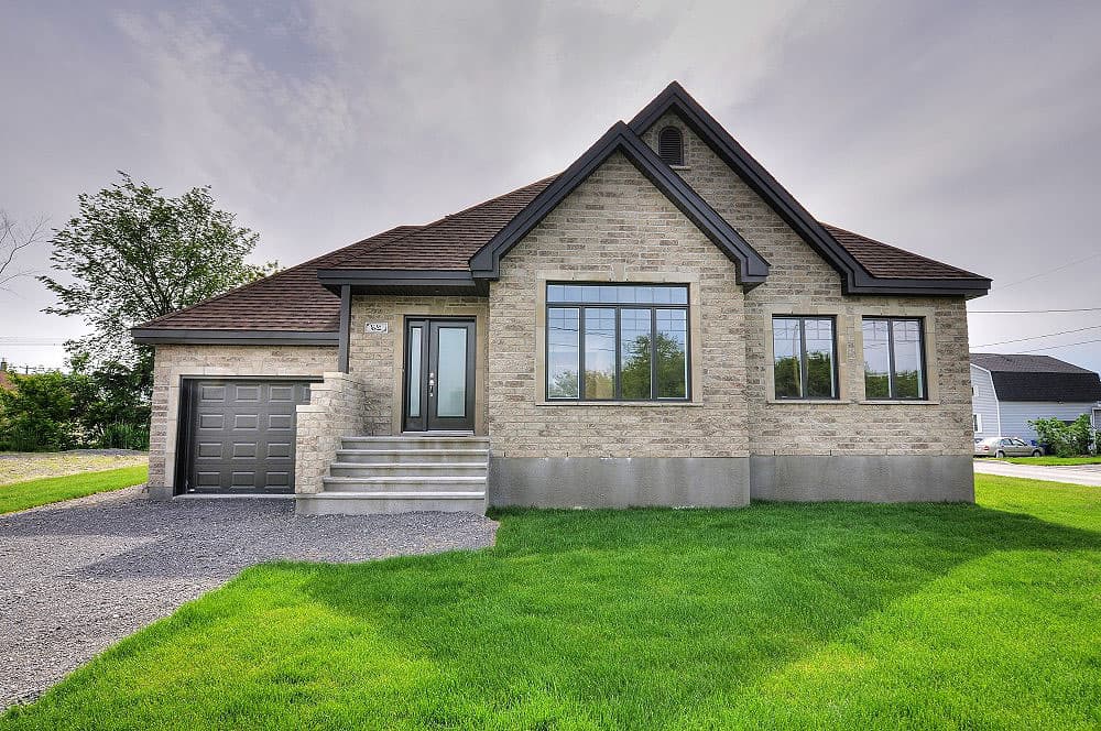House plan exterior: One-story brick home with attached garage, gabled roof, covered entry with stairs, and large picture window.