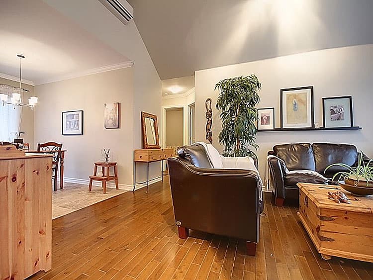 Interior view of a living and dining area with leather sofas, a wooden coffee table, and hardwood floors.