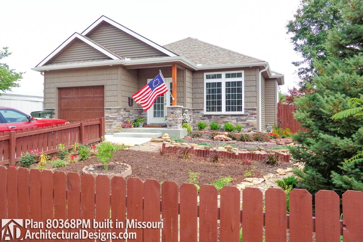 House plan exterior: Single-story home with attached garage, stone accents, gable rooflines, and covered front porch.