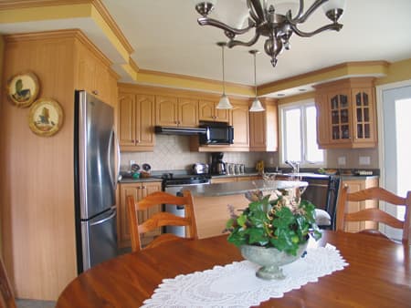 Kitchen with wood cabinets, stainless steel refrigerator, island, and dining table.