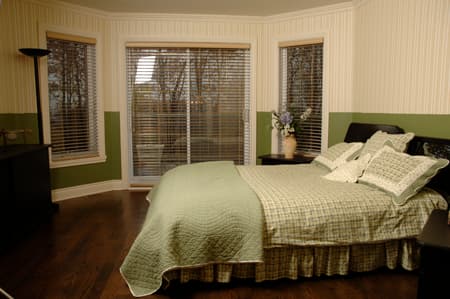 Bedroom with queen bed, bay windows, and sliding glass door leading outside.