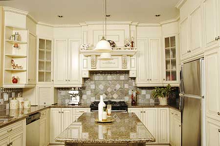 Kitchen with cream cabinetry, a central island, stainless steel refrigerator, and decorative backsplash tiles.