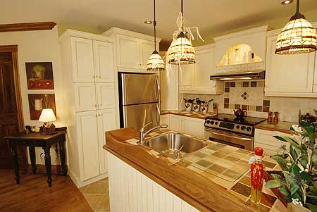 Kitchen with white cabinets, stainless steel refrigerator, double sink, stovetop and decorative pendant lighting.