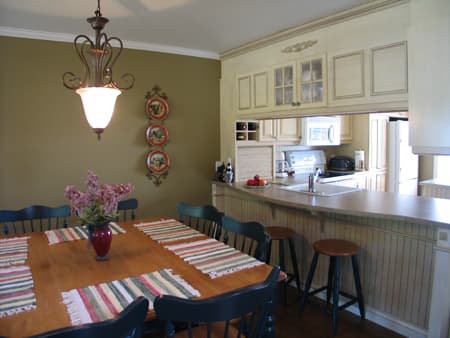 Dining area with wooden table and chairs adjacent to kitchen pass-through with counter seating.