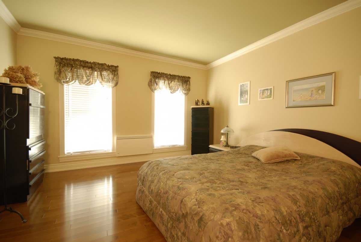 Bedroom interior with a bed, two windows, a dresser, and wood flooring. Architectural rendering.
