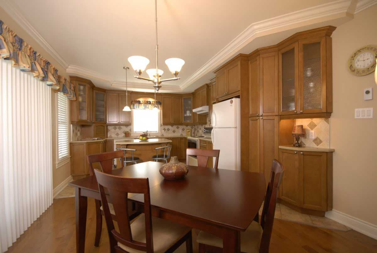 Kitchen with light oak cabinets, island with seating, dining table, and white vertical blinds.