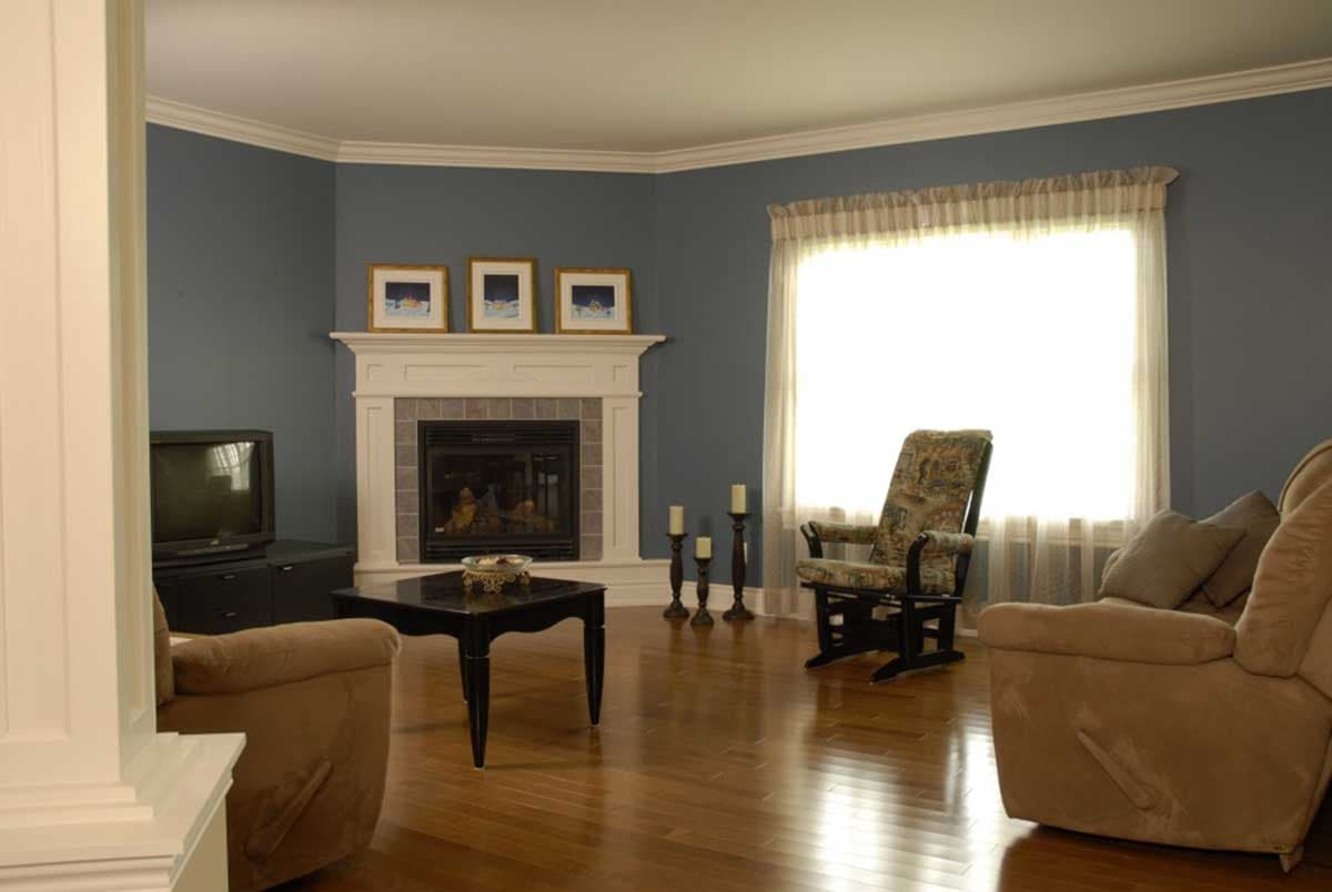 Living room with fireplace, large window with sheer curtains, and two chairs.