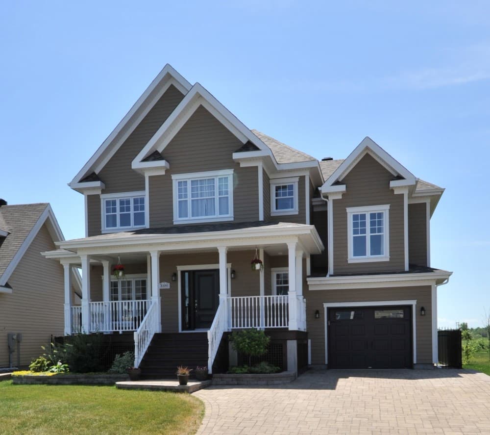 House plan exterior: Two-story home with a wraparound porch, multiple gables, and an attached two-car garage.