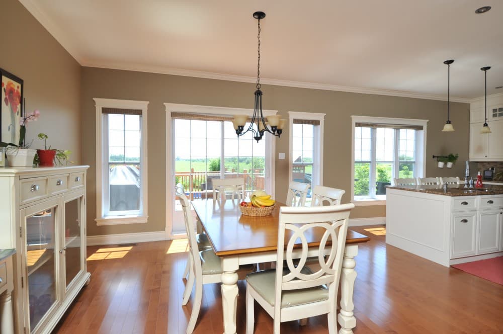 Dining area and kitchen with island, chairs, dining table, and windows overlooking a deck.