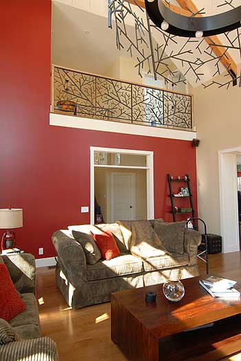 Interior living room with open loft and decorative branch railing. High ceilings with exposed beams.