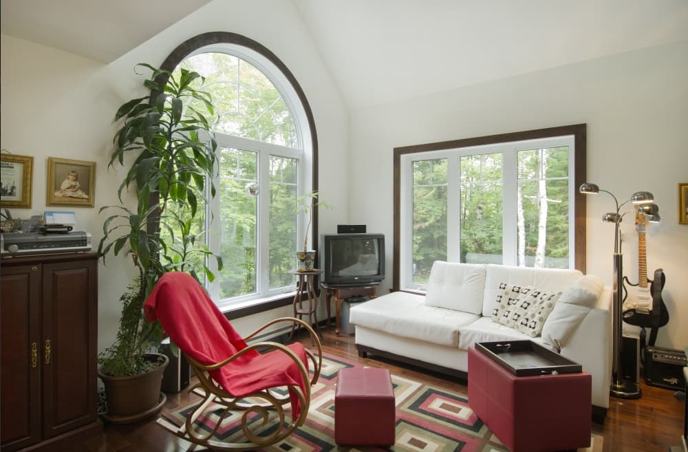 Living room interior with arched window, sofa, rocking chair, and television.