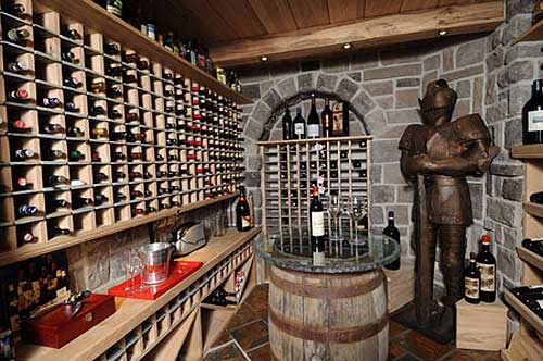 Wine cellar with extensive built-in wood shelving, a stone wall, and a knight's armor statue.