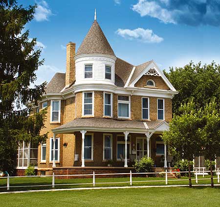 House plan exterior of a two-story Queen Anne style home with a prominent turret, wraparound porch, and decorative gable.