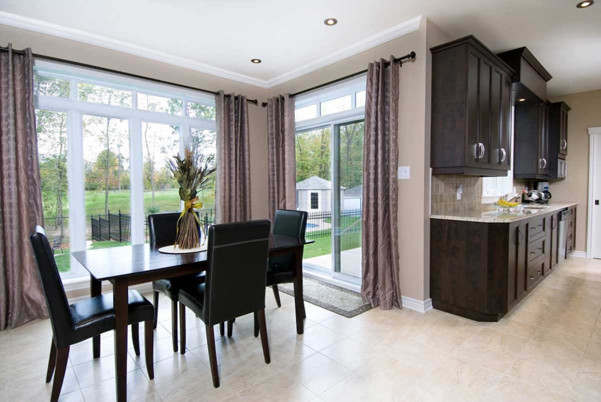 Dining area and kitchen with dark wood cabinets, granite countertops, and large windows overlooking the backyard.