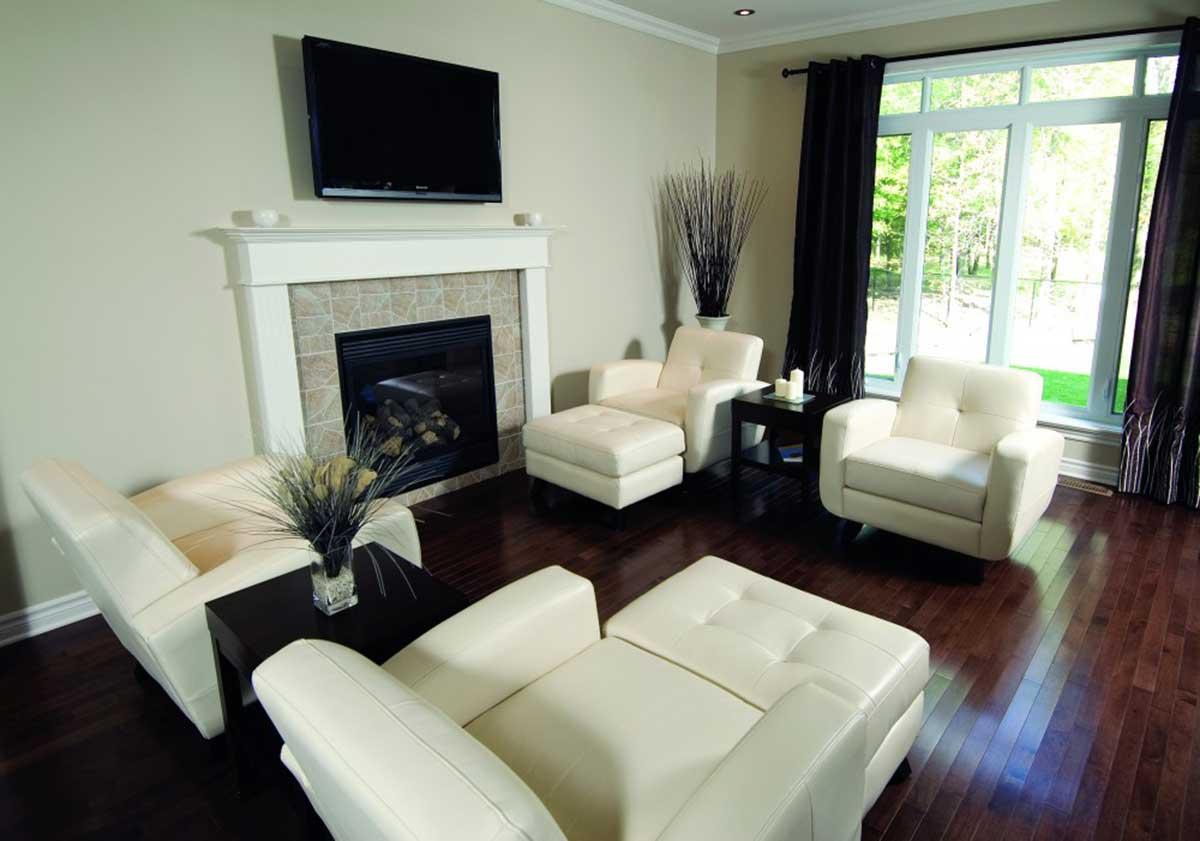 Living room with fireplace, TV, seating, and large windows overlooking outdoor greenery.