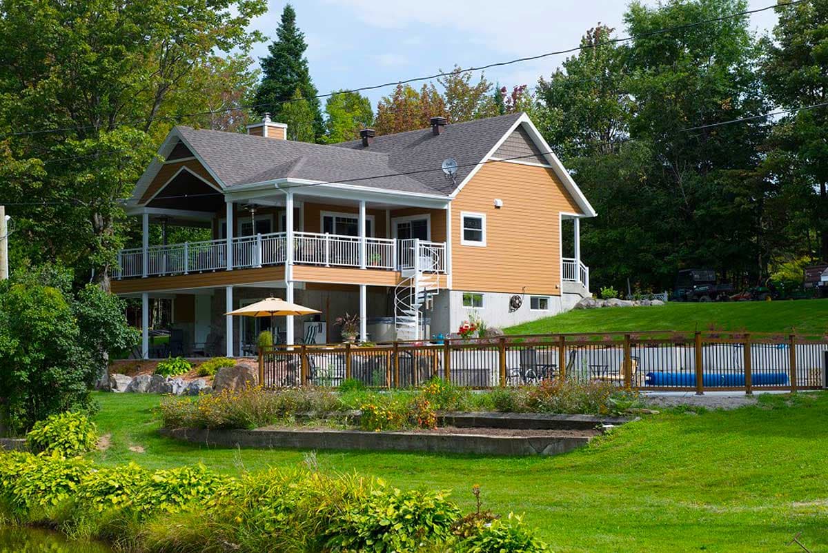 House plan exterior: Two-story Modern Farmhouse with wraparound deck, spiral staircase, and gabled dormers.