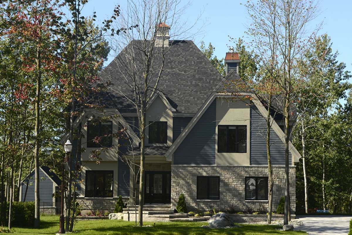 House plan exterior featuring a two-story design with stone and siding, multiple gables, and a prominent asymmetrical roofline.