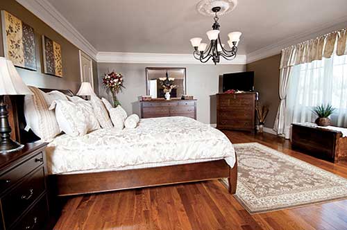 Primary bedroom with dark wood furniture, king bed, patterned rug, chandelier, and wall art.