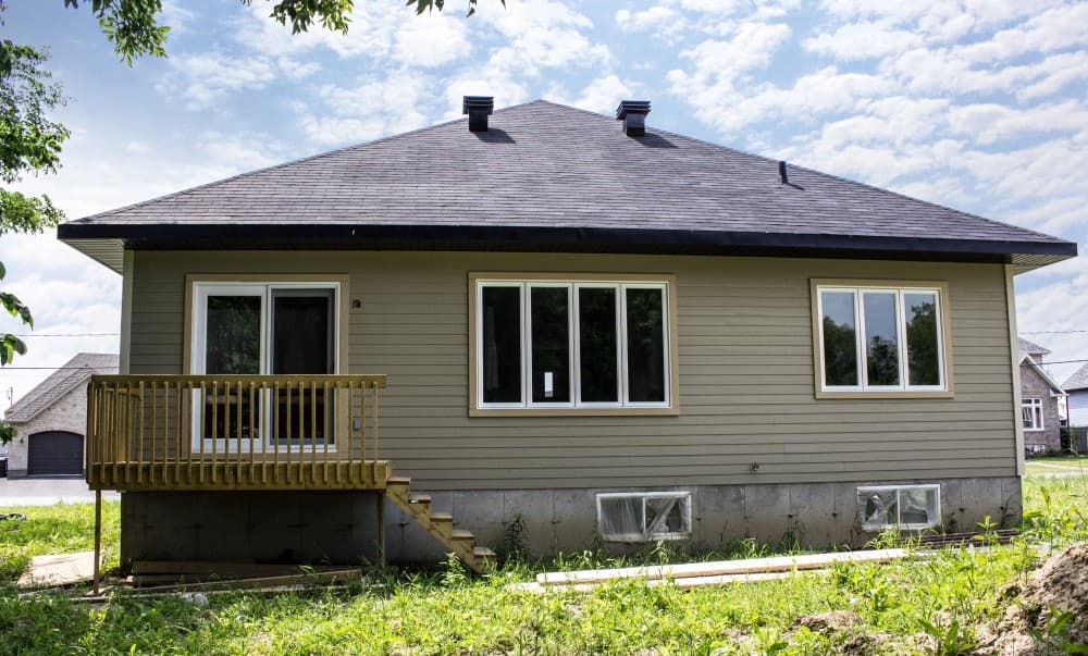 House plan exterior: Ranch style, single story, with a wooden deck, gable roof, and two chimneys.