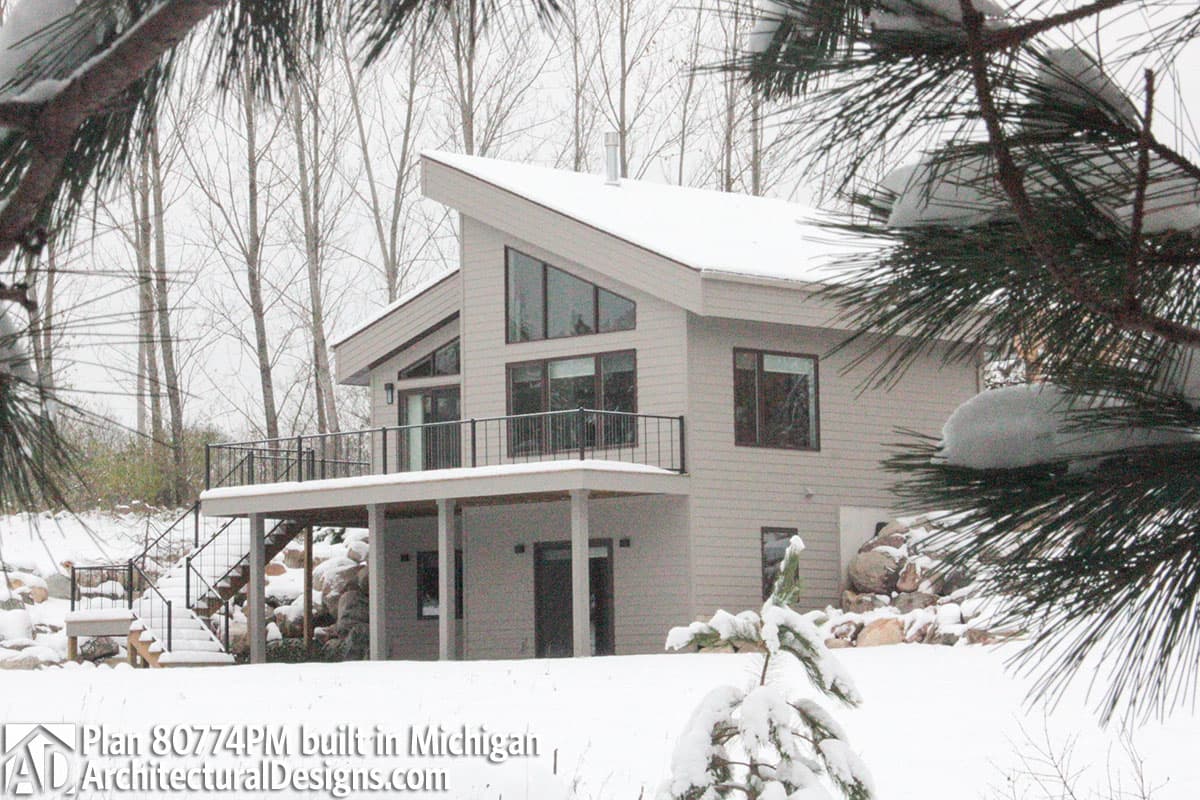 House plan exterior: Modern style, two stories, angled roofline, prominent gable window, and deck.