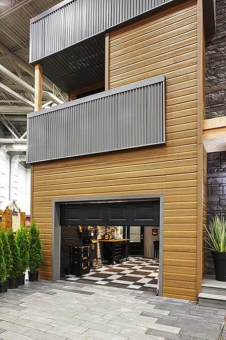 House plan exterior featuring wood siding, corrugated metal accents, a balcony, and a garage with a checkerboard floor.