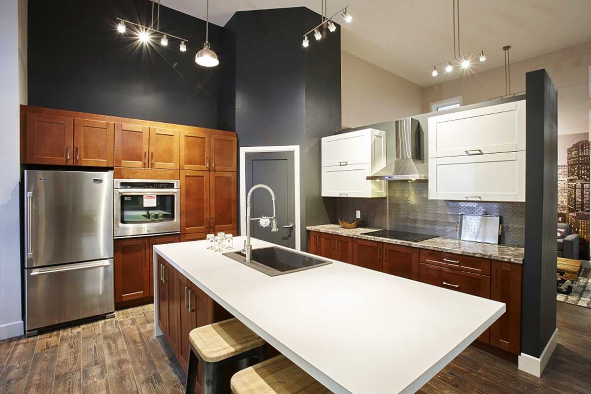Kitchen with stainless steel appliances, white quartz island, dark wood lower cabinets, and white upper cabinets.
