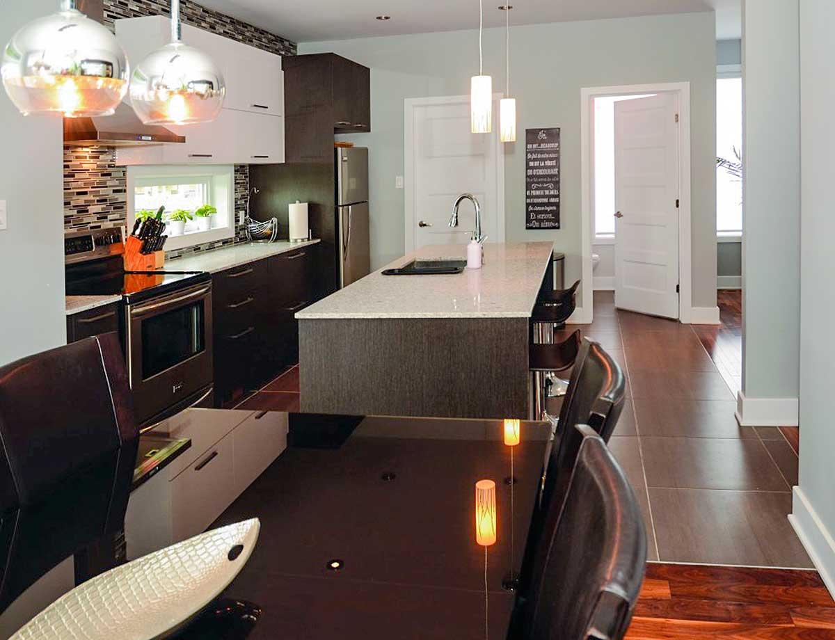 Modern kitchen with island, pendant lights, stainless steel appliances, tile backsplash, and dark wood cabinetry.