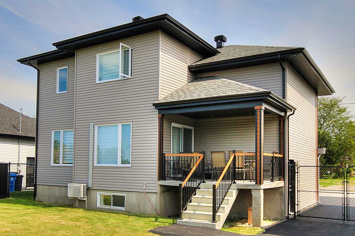 Two-story house plan exterior with beige vinyl siding, a covered porch with stairs, and black roof trim.